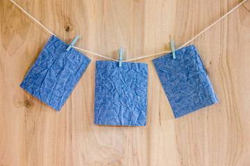 three blue sheets on clothespins hang on thread