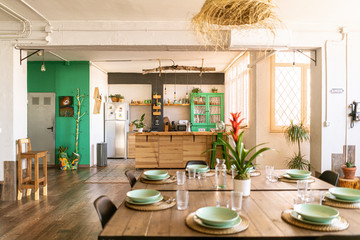 Interior design / decoration. Spacious open kitchen and dining room in bright industrial loft, with table set ready for a nice meal. © Malquerida Studio