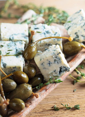 Pieces of blue cheese with preserved capers and branches of thyme.