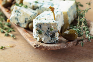 Pieces of blue cheese with preserved capers and branches of thyme.