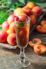 Apricot liqueur and juicy fruits on a wooden table.