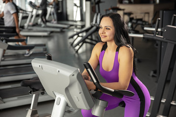 Fototapeta premium Upcoming. Young muscular caucasian woman practicing in gym with cardio. Athletic female model doing speed exercises, training her lower, upper body. Wellness, healthy lifestyle, bodybuilding.