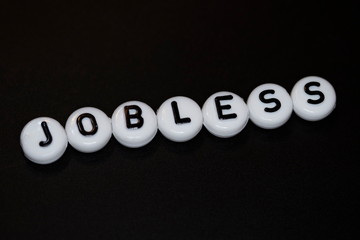 The word JOBLESS written on wooden cubes isolated on a black background...