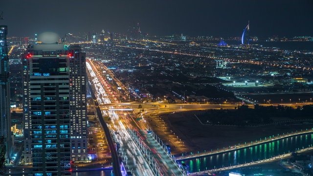 Dubai business bay towers illuminated at night timelapse. Rooftop view of some skyscrapers and new towers under construction.