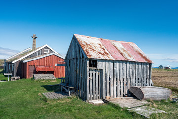 Old and weathered building on Flatey in Iceland. Factory pipe in the background. Blue sky during springtime