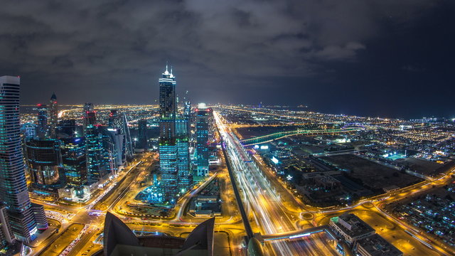 Dubai business bay towers illuminated at night timelapse. Rooftop view of some skyscrapers and new towers under construction. - Powered by Adobe