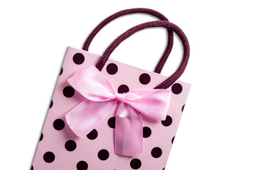 Pink gift bag with polka dots with a bow on a white background. View from above. Flat lay.