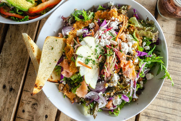 A bowl of green salad with salmon and feta. Healthy lunch
