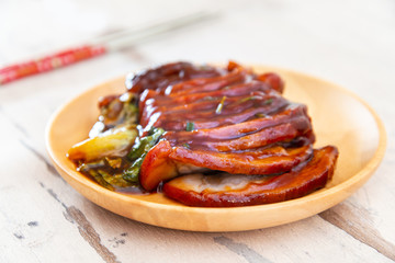 Chinese lacquered pork slices with its caramelized sauce prepared for eating in a wooden plate