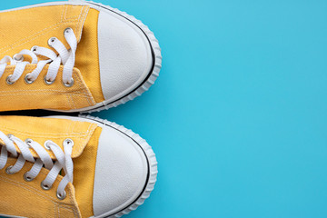 Yellow summer youth sneakers on a blue background with copy space