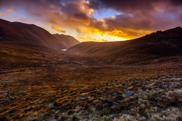 Naklejka premium Beautiful valley with water reservoir in Mourne Mountains at golden hour and dramatic sunset. Mourne Mountains, highest range in Northern Ireland