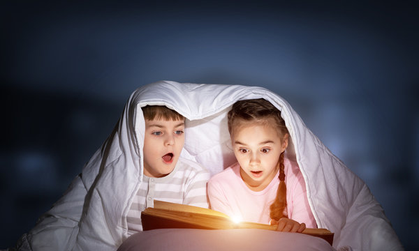 Children Reading Scary Stories In Bed