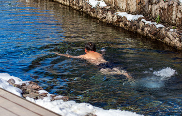 A man bathes in a river in winter