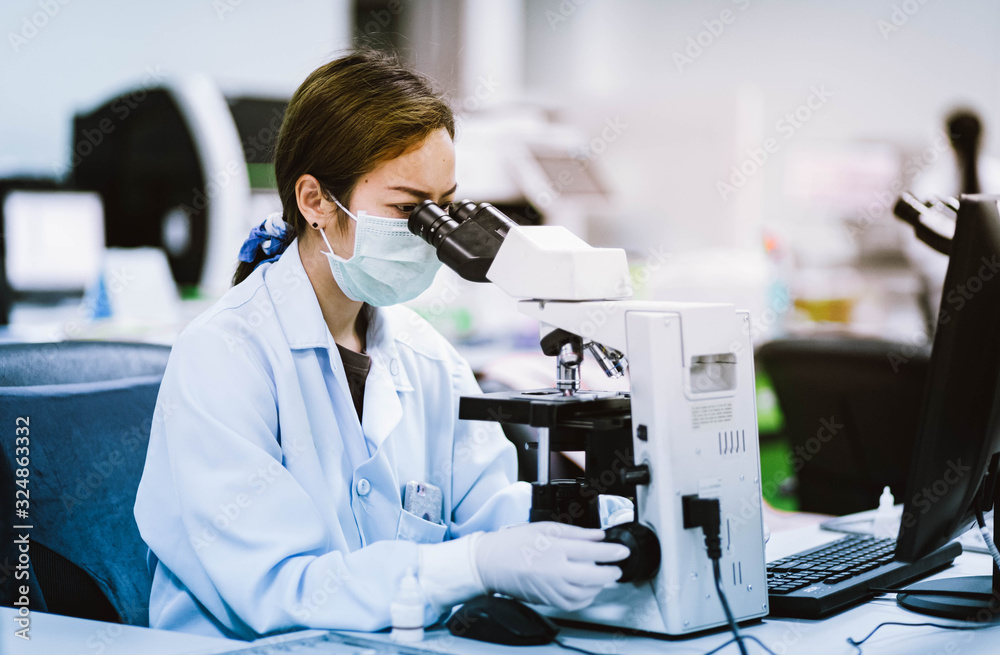 Wall mural medical technician look at the microscope in medical laboratory