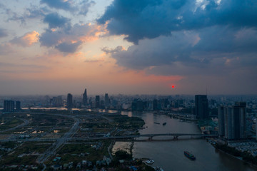 Dramatic aerial view of Saigon river and Ho Chi Minh City skyline at sunset with beautiful stormy and brightly colored clouds in the sky