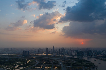 Dramatic high aerial view of Saigon river and Ho Chi Minh City skyline at sunset with beautiful stormy and brightly colored clouds in the sky