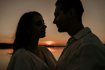 Young couple is embracing on the sunset coast. Two silhouettes against the sun. Romantic love story.
