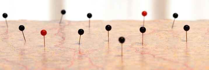 panoramic image and closeup of pin sticks into a real map. travelling to. pin marking location on map. maps navigation with red and black color point markers design background.