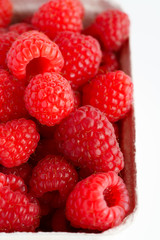 Freshly picked organic raspberries in recycled paper cup. High resolution, white background