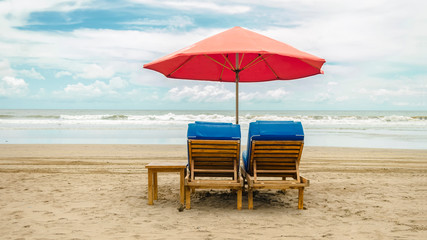 Two sun loungers and a beach umbrella in the sand overlooking the sea. Beach concept