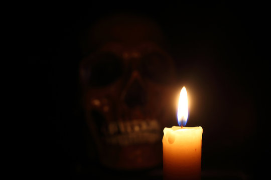 Skull and candle. Halloween or black magic concept. Focus on candle