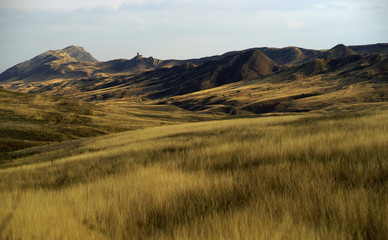 Beautiful landscape of colorful hills with yellow grass just before sunset, desert in autumn time in south of Georgia