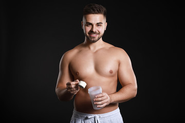 Sporty man with protein on dark background