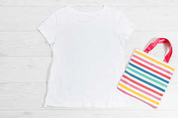 White closeup t shirt mock up flat lay on white wooden background. Top view and copy space. Mockup...