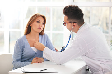 Male cardiologist examining female patient in clinic