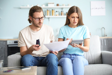 Worried young couple in debt at home