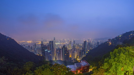 The famous view of Hong Kong from Victoria Peak night to day timelapse. Taken before sunrise with colorful clouds over Kowloon Bay.