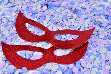 red brazilian carnival party costume mask on colorful confetti background with space for text,