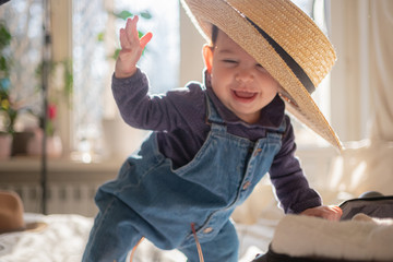 Little infant girl in straw hat smiling and laughing. Family lifestyle