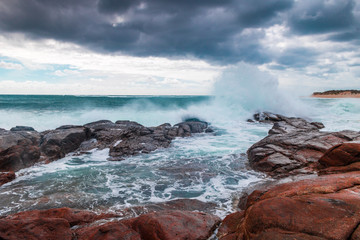 Waves dark clouds red rocks beach Australia