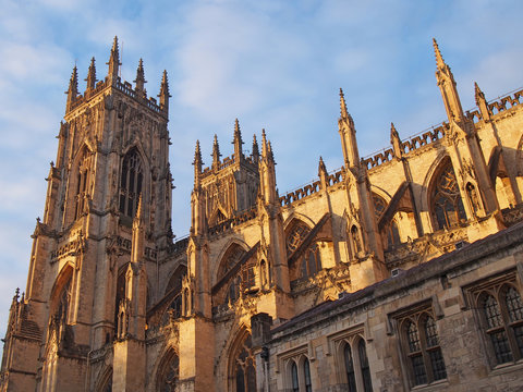 a side view of york minster in sunlight against a blue cloudy sky
