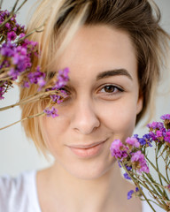 Young woman holds a bouquet of purple flowers near her face - 324881914