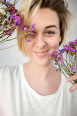 Young woman holds a bouquet of purple flowers near her face - 324881929