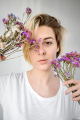 Young woman holds a bouquet of purple flowers near her face - 324881944