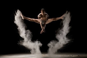 Naklejka na ściany i meble Male gymnast jumping in dust cloud view