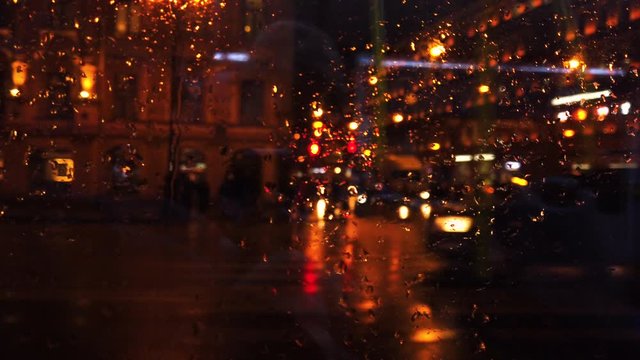 Defocused lights and transport in night city street while it is rainnnig. Rainy night street view throught public transport window at Saint-Petersburg, Russia