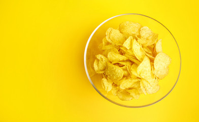 Many potato chips on yellow background. Top view