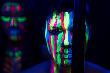 Close-up view of man with fluorescent make-up and stick