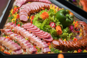 Salami sausages sliced with pepper, garlic and rosemary on cutting board on wooden table