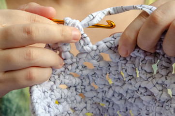 close up on hands doing crochet with a golden needle and white thread