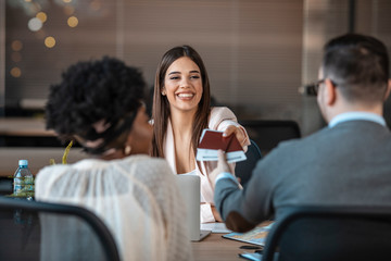 A young man and a woman came to the travel agency. They want to go on a trip during their holidays. Female travel agent giving tickets to young happy couple.