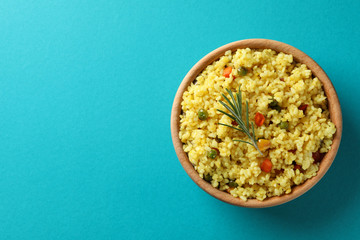 Wooden bowl with delicious rice on turquoise background, top view