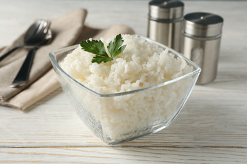 Composition with bowl of delicious rice on wooden background, closeup