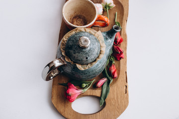 tea pot with a cup with flowers on white table