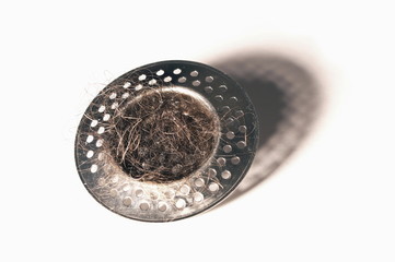 clogged strainer with hairs on white background. 