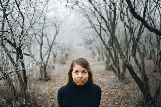 Woman with tape on her mouth in cold winter forest